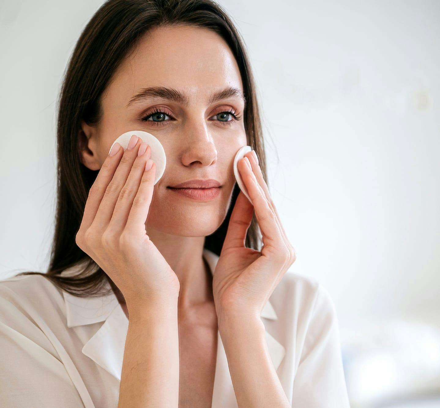 woman appling facial product with cotton pads