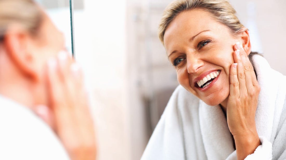 woman smiling with hand on face