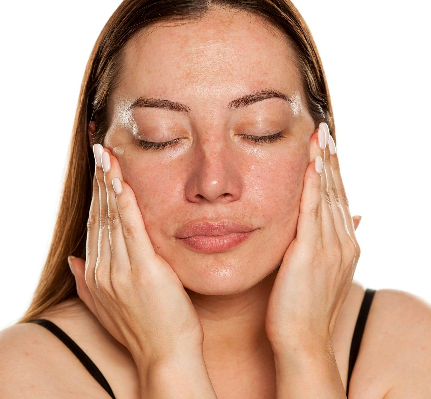woman with eyes closed washing face