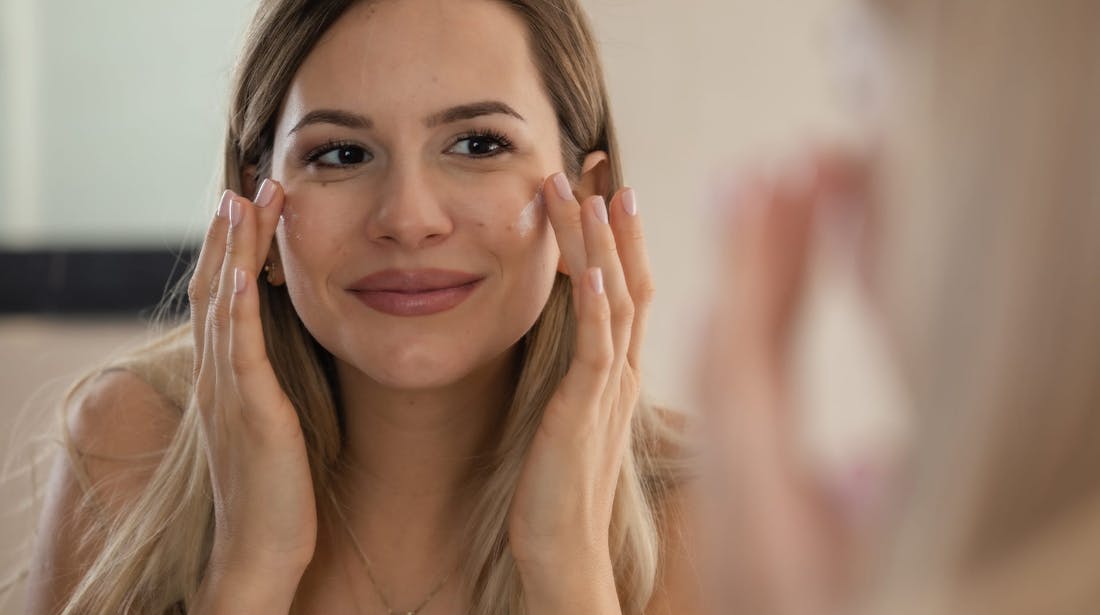 woman applying cream to face