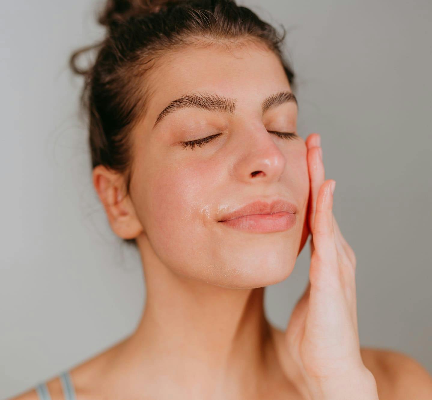 woman with eyes closed applying facial cream