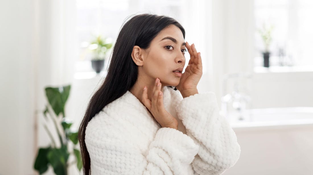 woman inspecting face in mirror