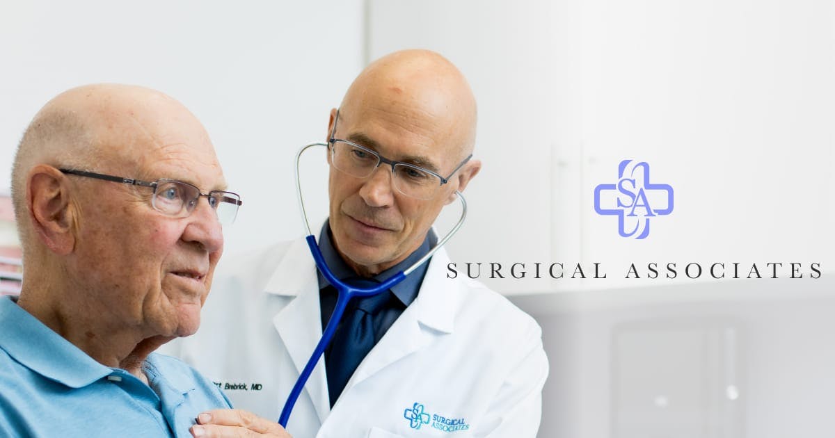 Doctor treating a patient with the Surgical Associates logo on top