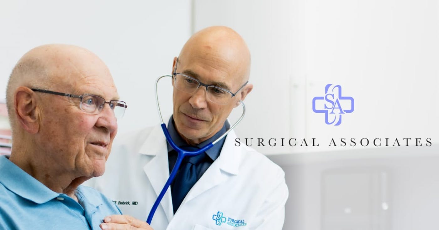 Doctor treating a patient with the Surgical Associates logo on top