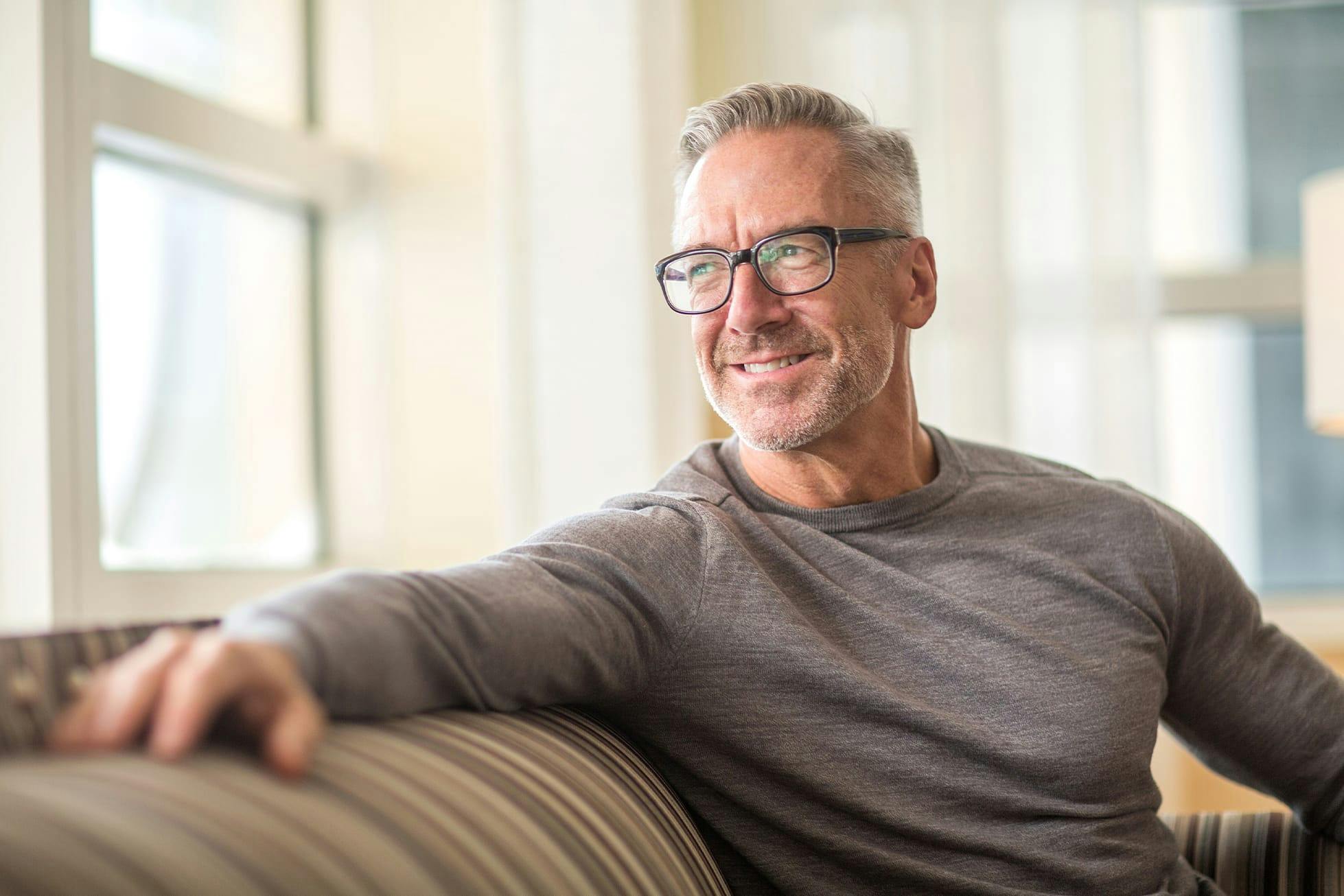 man sitting on couch looking out window