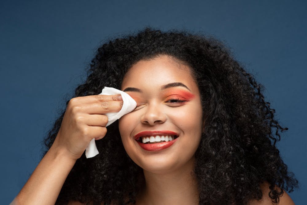 woman smiling and rubbing off makeup