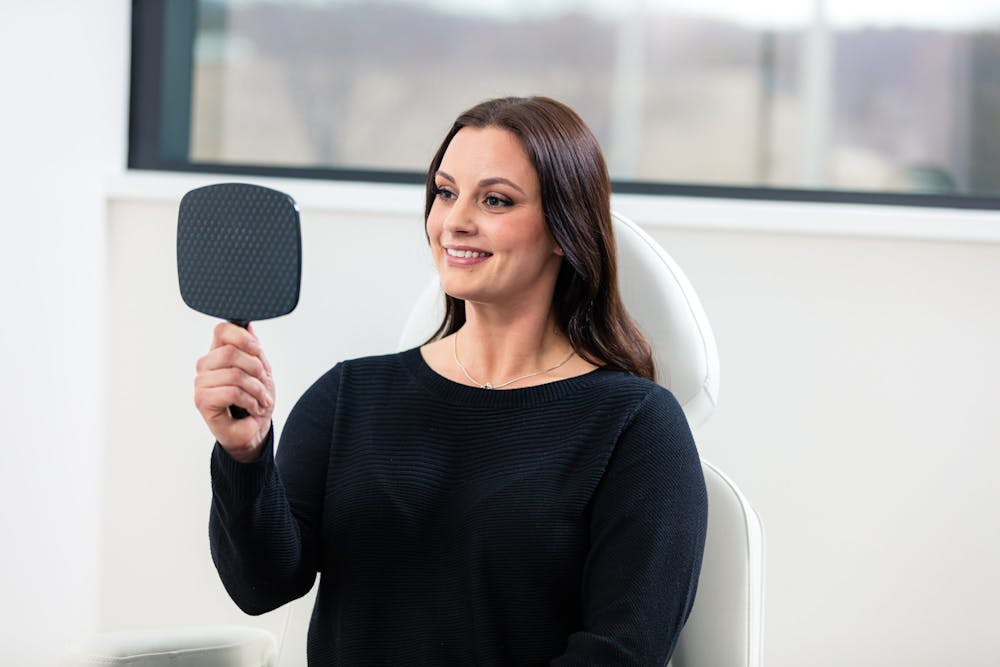 woman smiling and looking at mirror
