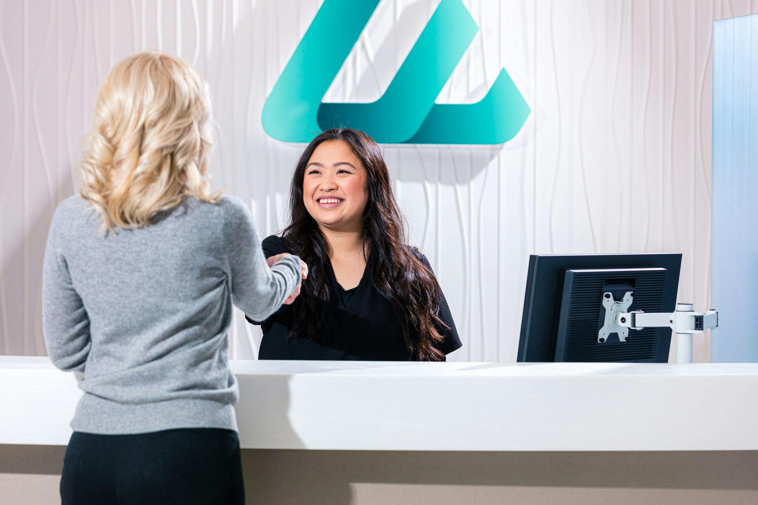 Eleve receptionist smiling and shaking patient's hand