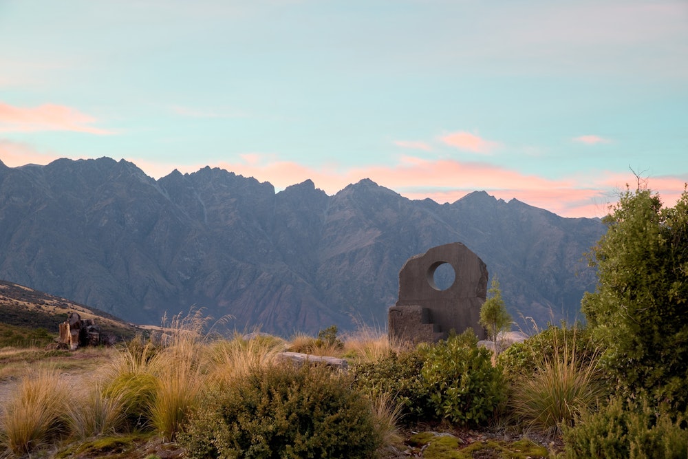 A large stone monolith sculptural seat in a beautiful location with mountains