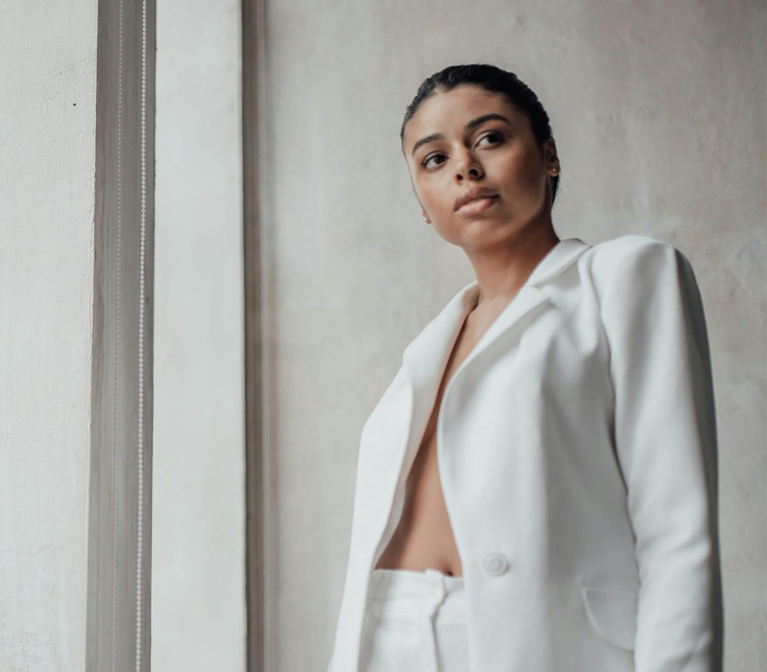 woman in white, leaning against a wall
