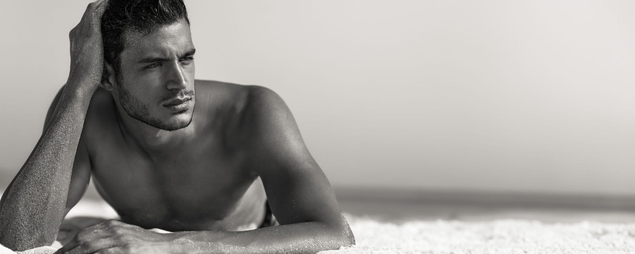 shirtless man lying on the beach