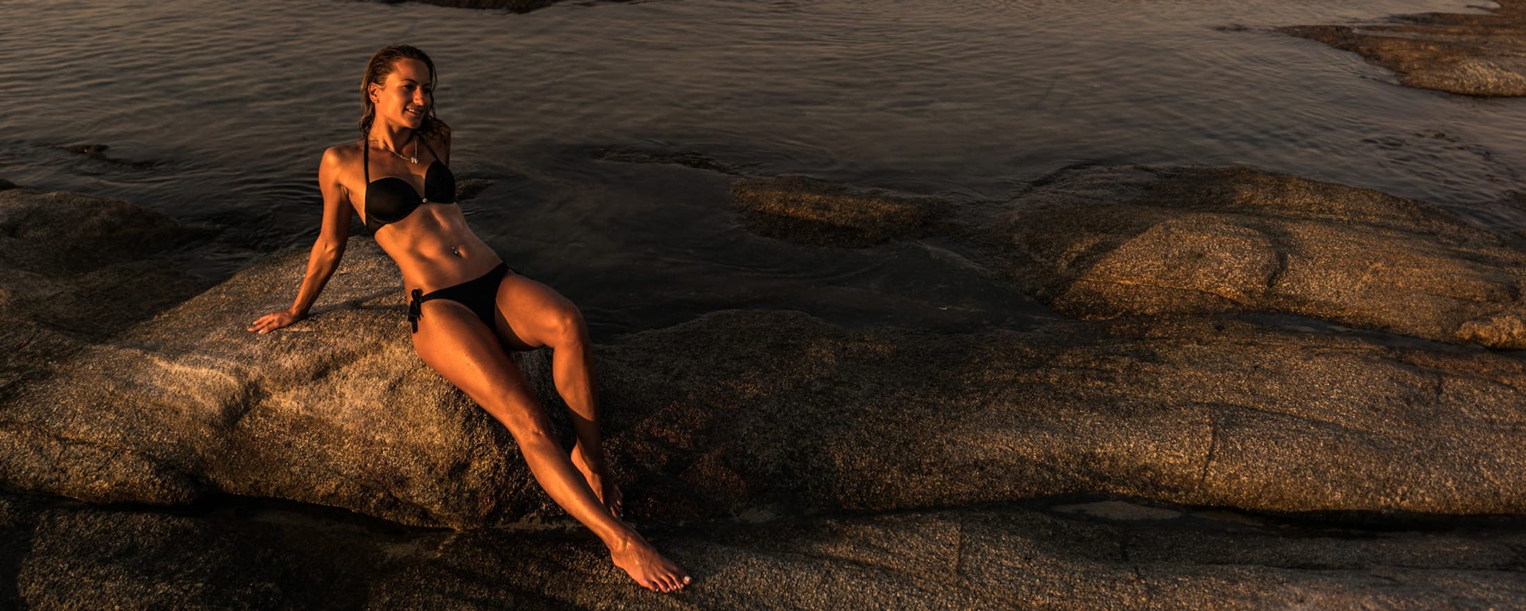 woman in a bikini laying on a rock