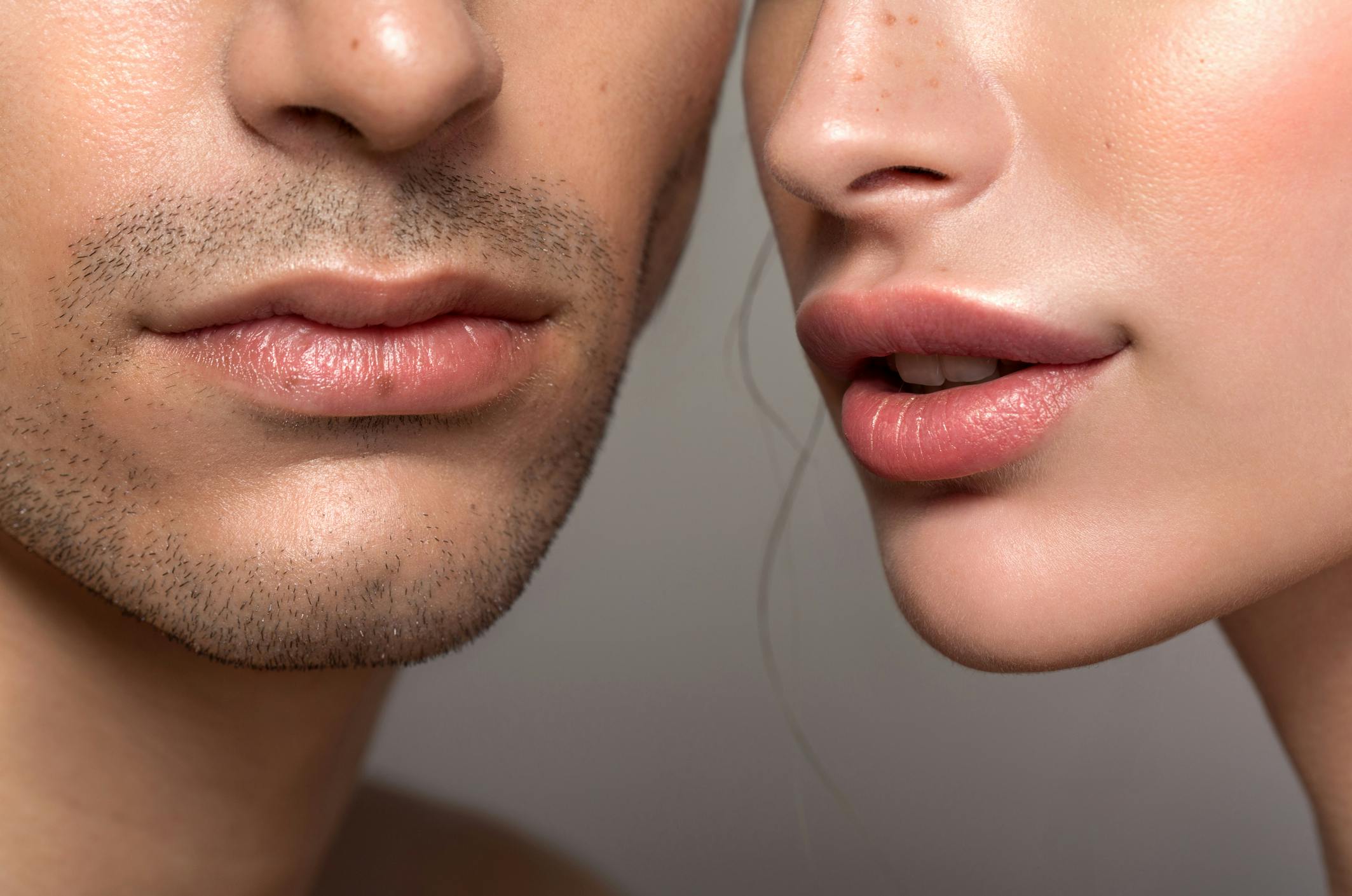 A man and woman's faces side by side but the photo cuts off their eyes to emphasize their lips.