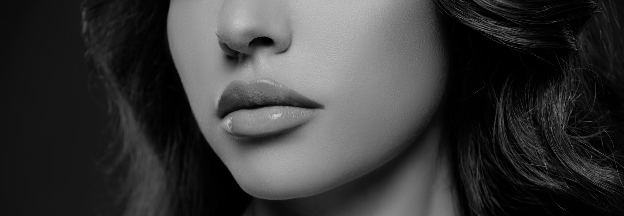 studio shoot where you can only see the bottom half of the brunette woman's face to emphasize her gorgeous lips