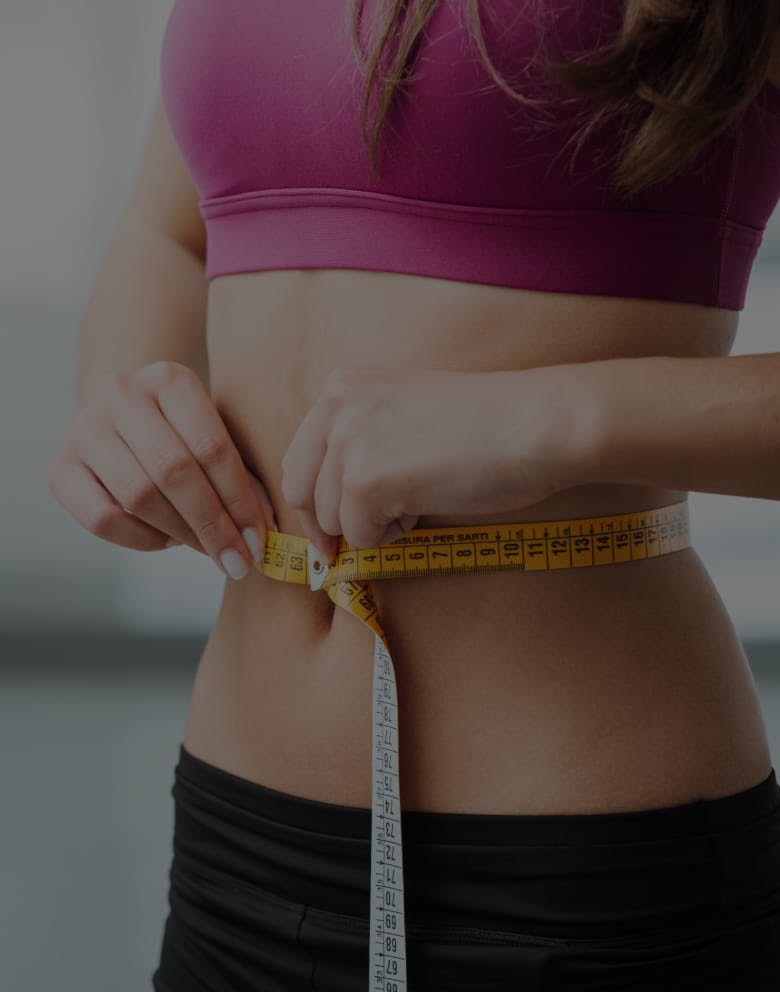 woman measuring waist after visiting the med spa in Orlando, FL