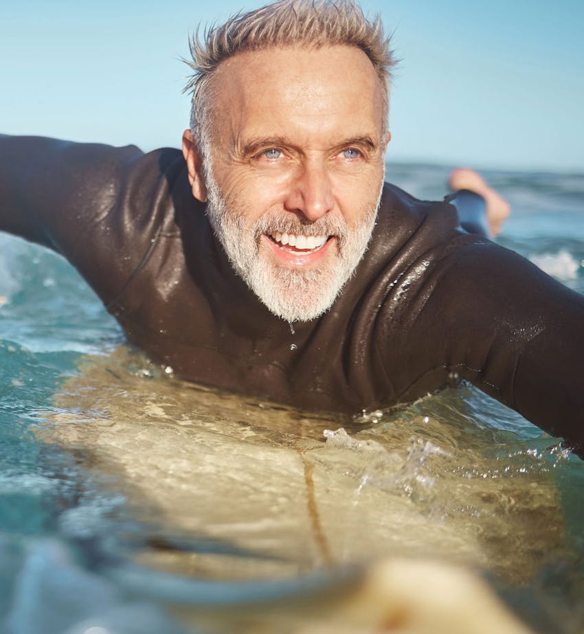 Happy man surfing after exercise guidance from Serotonin Centers.