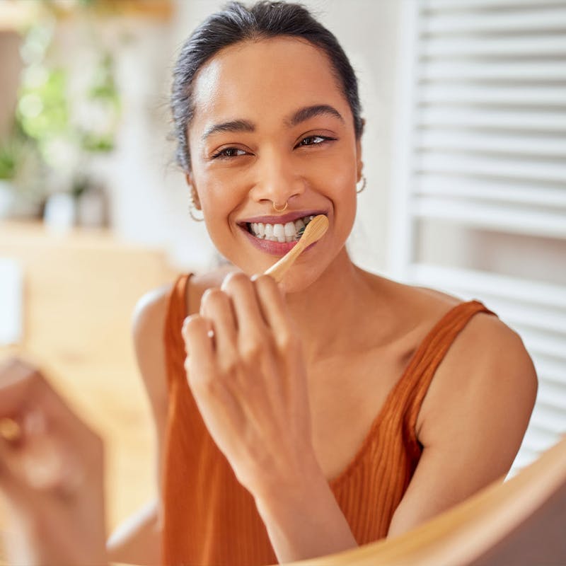 Happy woman brushing her teeth after nutrition guidance from Serotonin Centers.