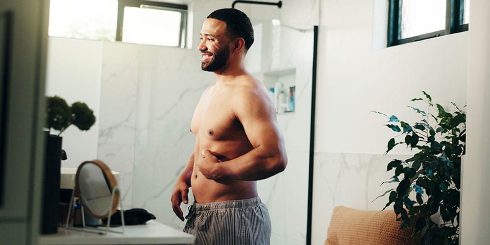 man looking in the mirror after starting his medical weight loss plan