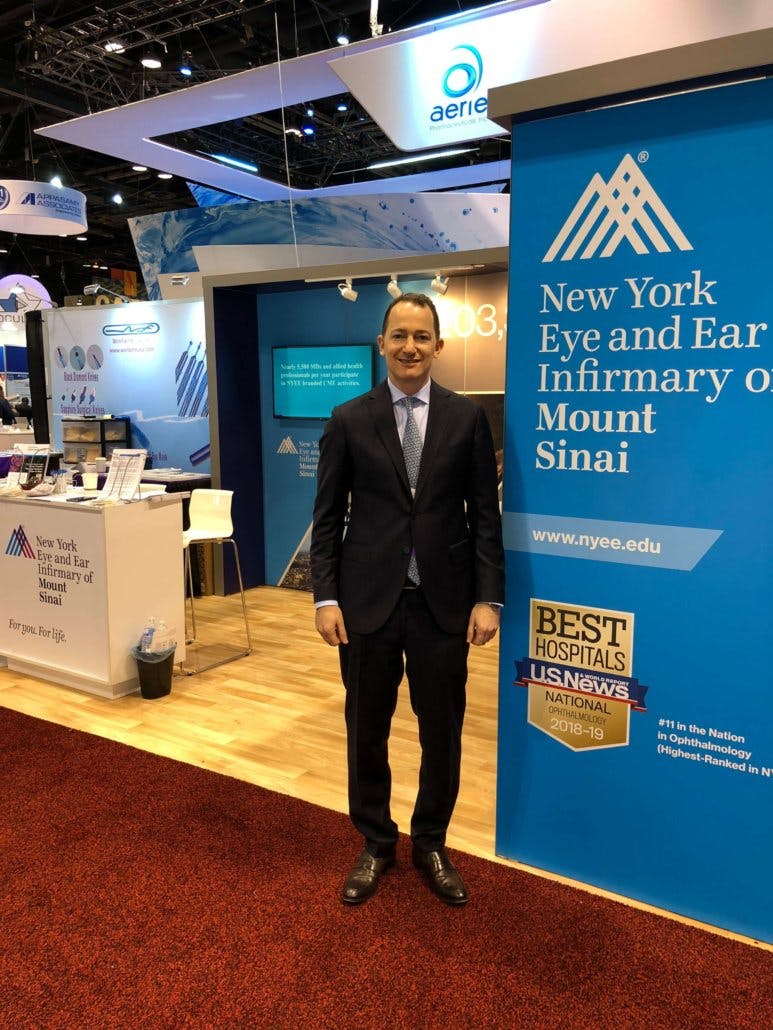 dr raviv at an expo in front of his booth