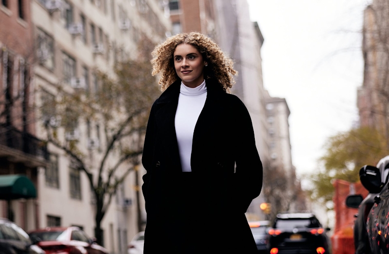 woman in long coat walking down city streets