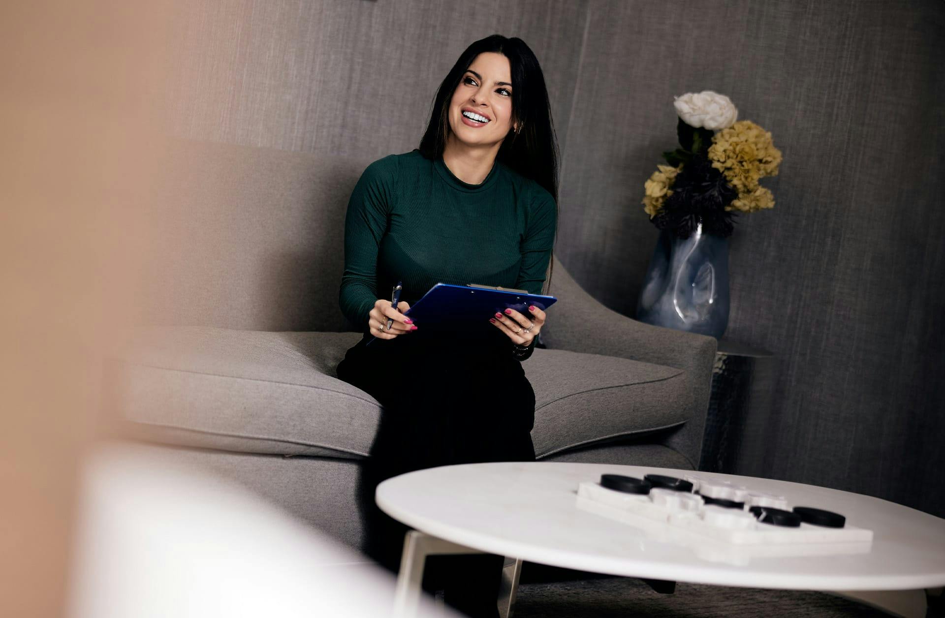 smiling woman sitting on a couch holding a tablet