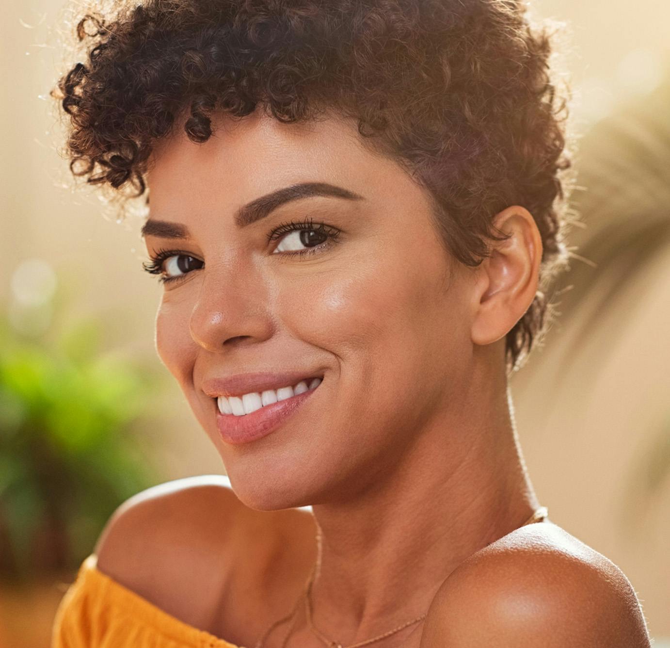 lady with short curly hair smiling in yellow top