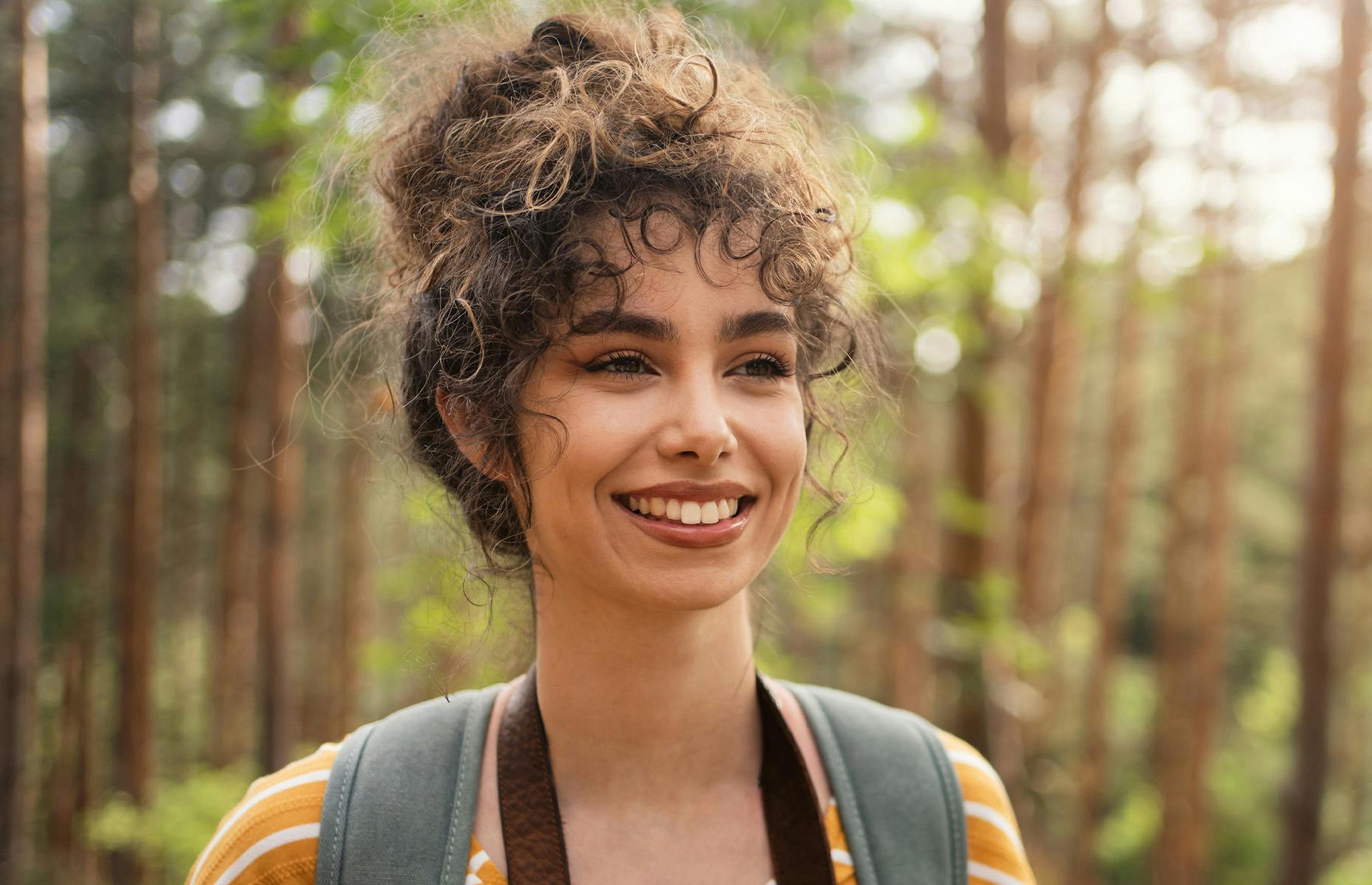 lady with messy bun in woods hiking