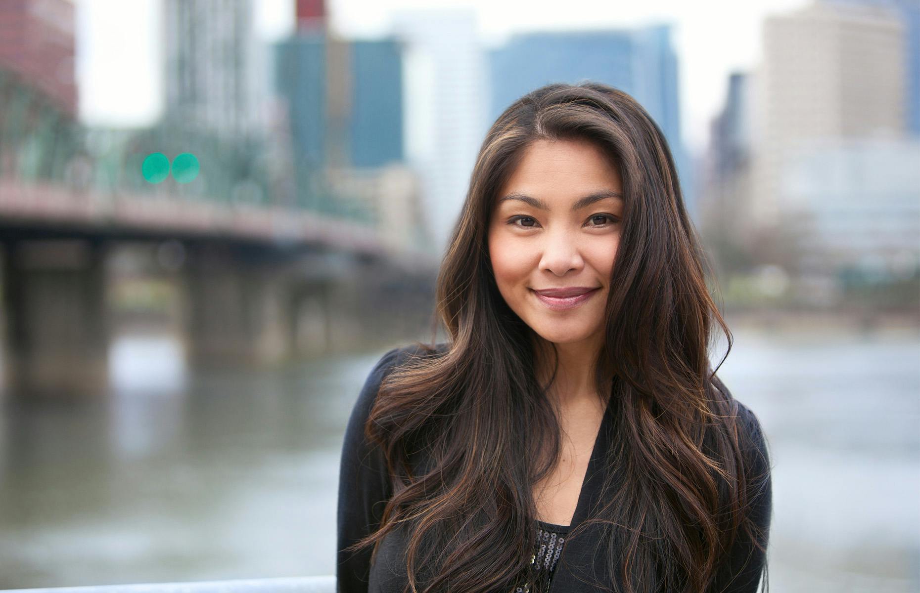 lady posing with water and bridge behind her