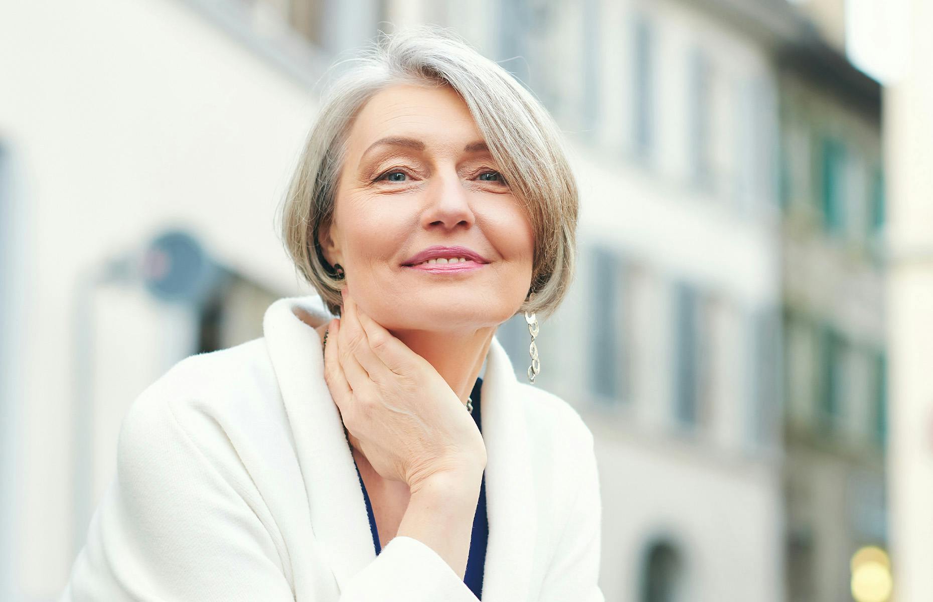older woman with short hair touching her neck