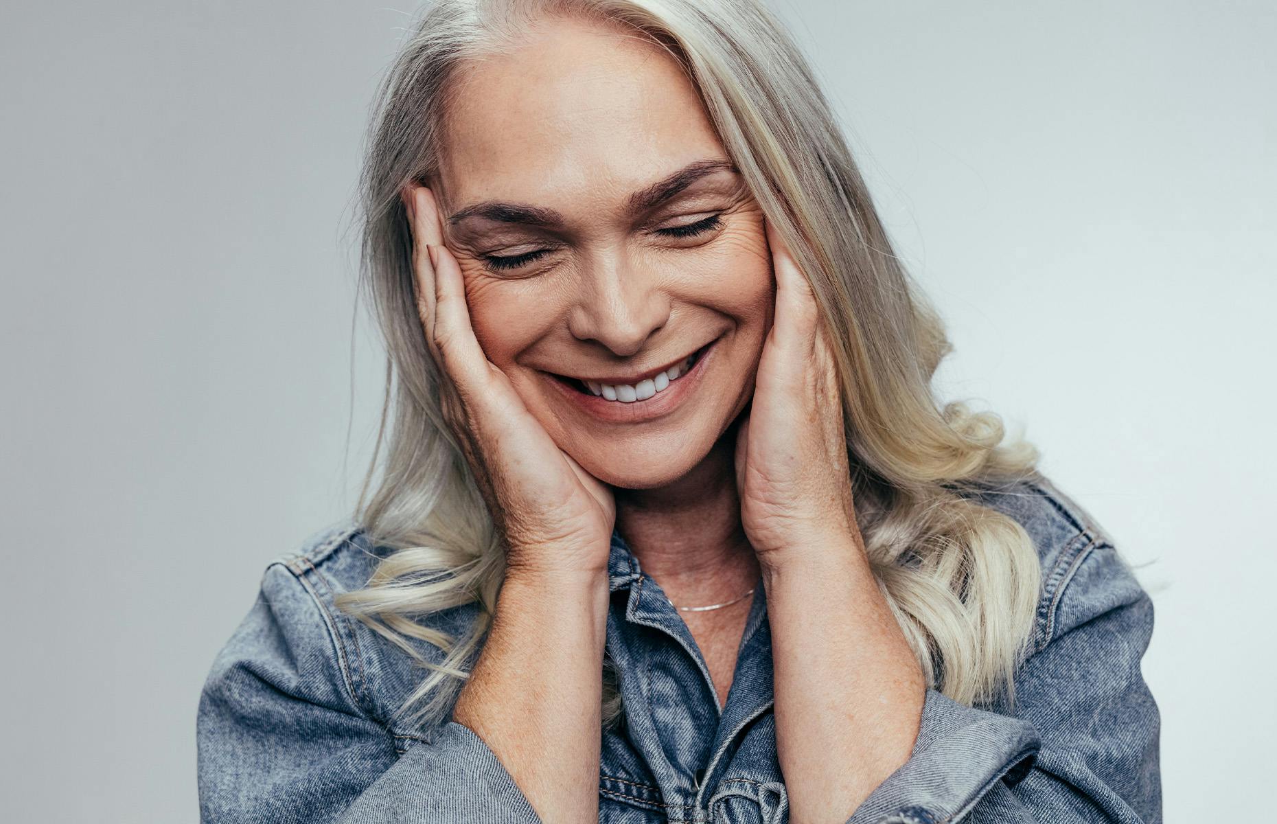 older woman looking down with her hands on her ears