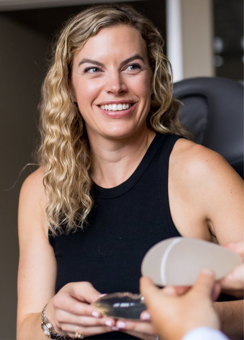 lady smiling while holding a silcone breast