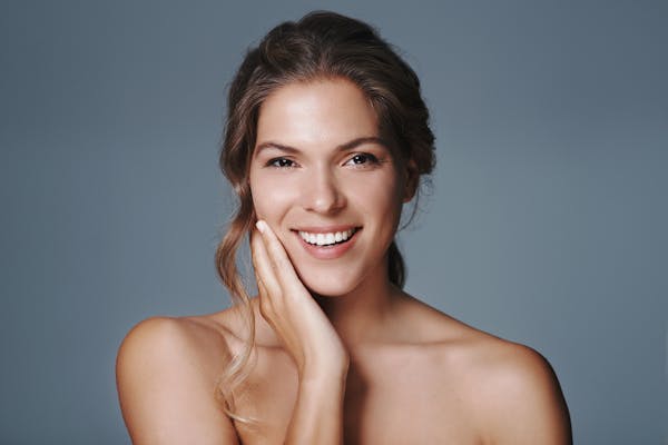 smiling brunette woman holding her cheek