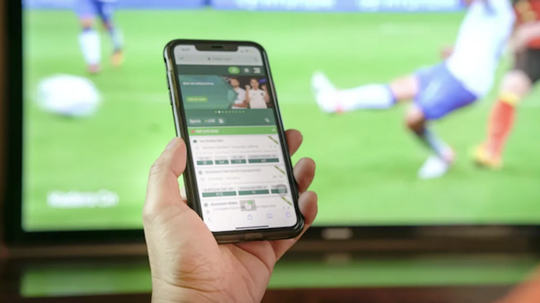 Celular em tela de apostas acompanhando jogo de futebol