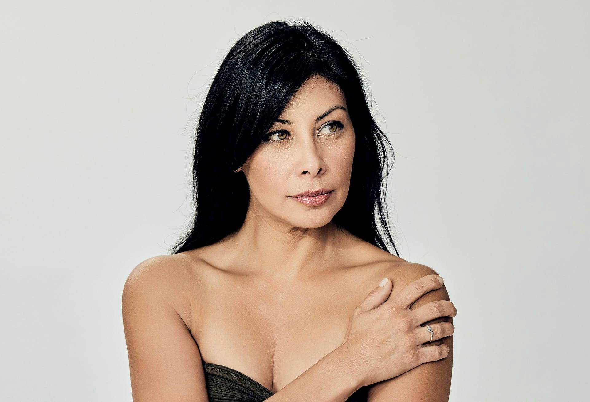 woman with black hair with hand on her shoulder