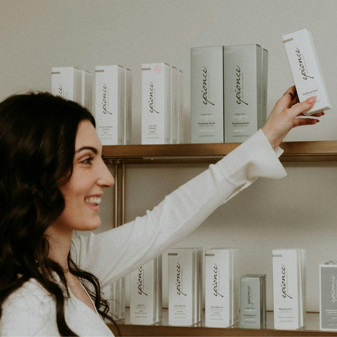 woman grabbing a skincare product off of a shelf