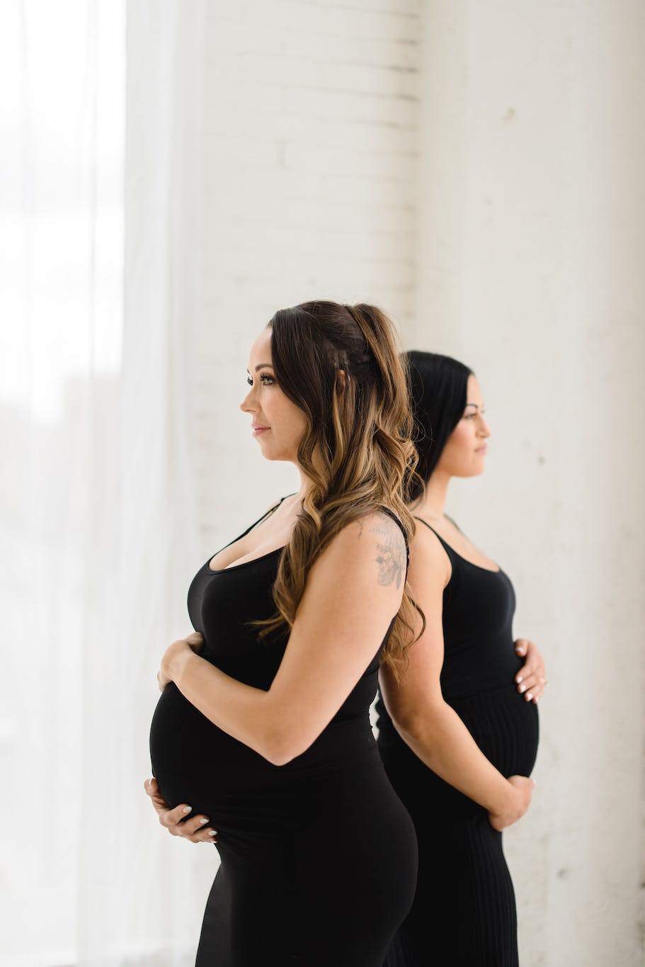 two pregnant women standing back to back