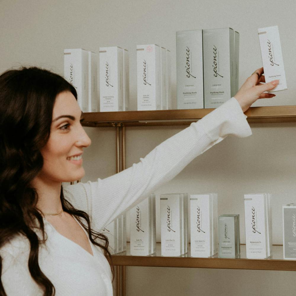 woman grabbing a skincare product off of a shelf