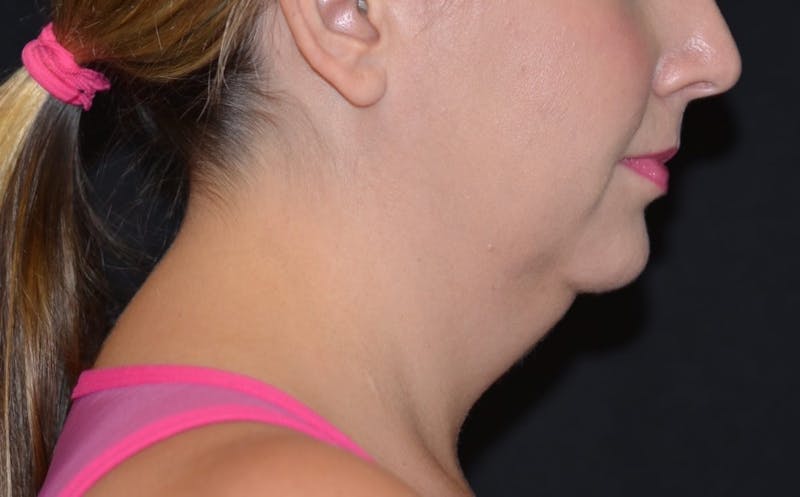 a close up of a woman with a ponytail and a pink top