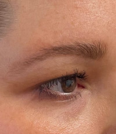 a close up of a woman's eye with a pair of scissors in her hand