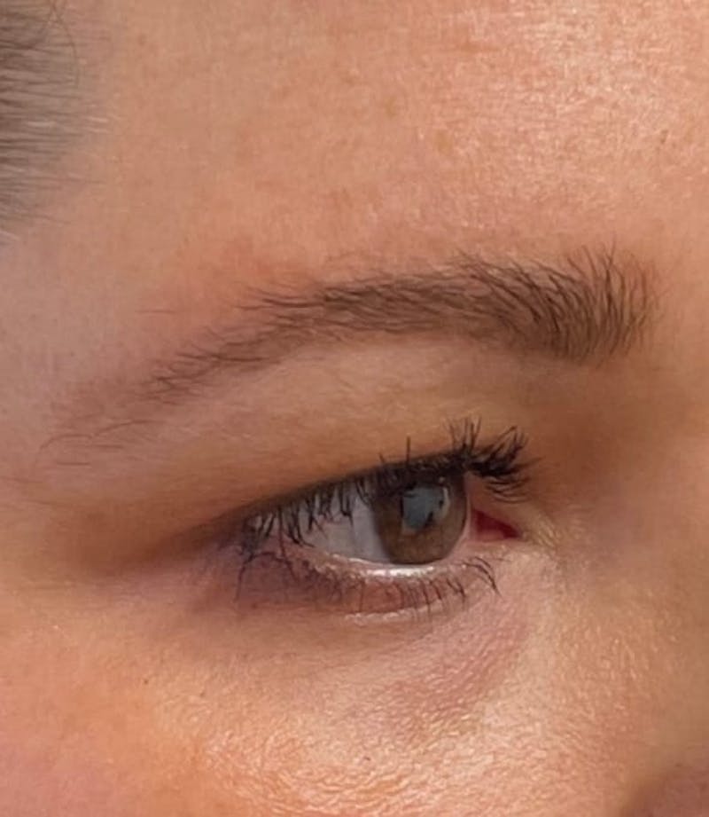 a close up of a woman's eye with a pair of scissors in her hand