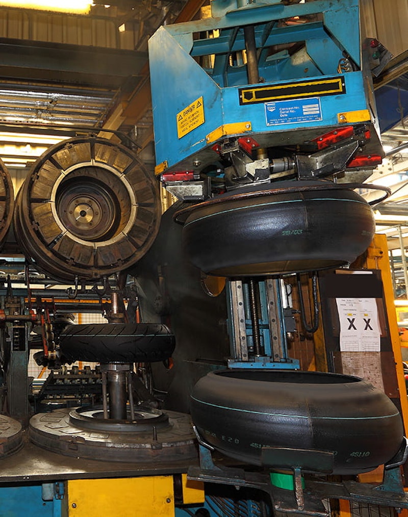 The cured tyre, left of picture with tread, has just come out of the mould. On the right, two green tyres await their turn. In the curing mould, the raised outer edges will be shaped to form the sidewalls and the tread will be created.