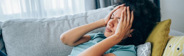 woman laying down holdnig her head in discomfort