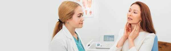 patient touching their neck while talking with doctor