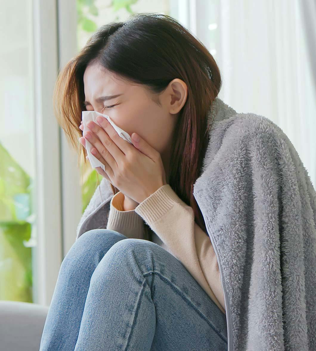 woman sneezing into tissue