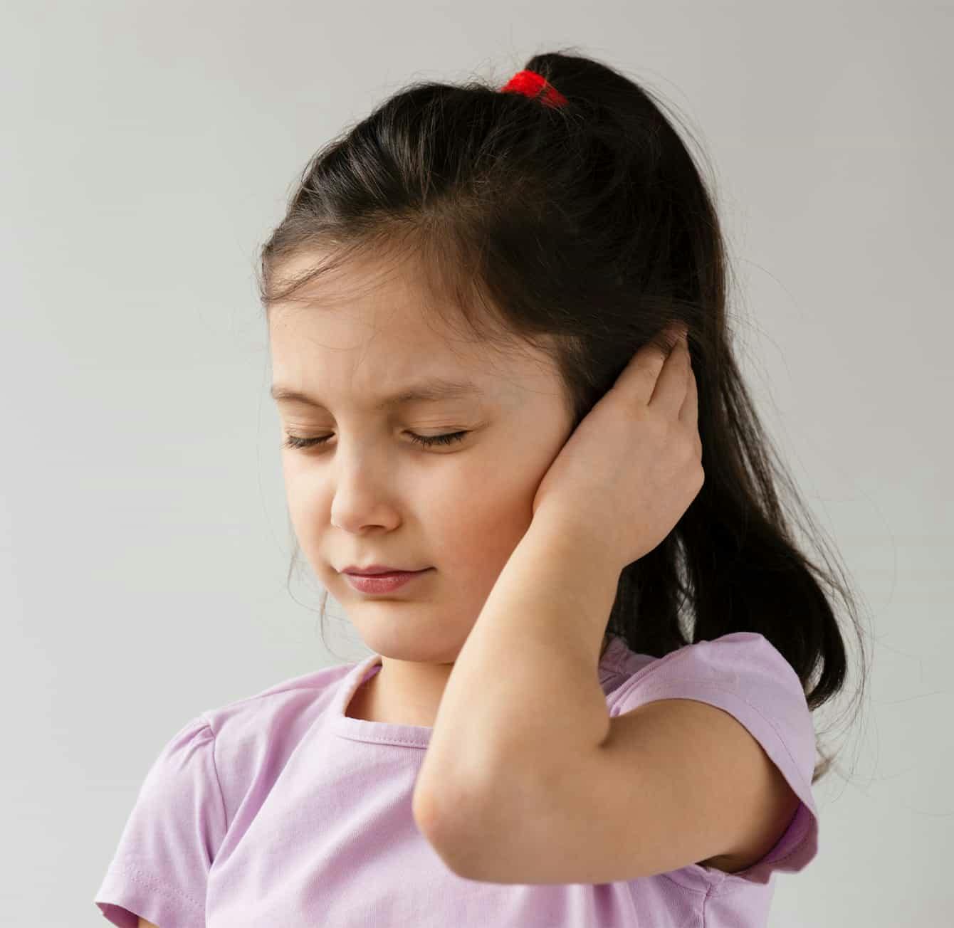 Child holding ear in discomfort