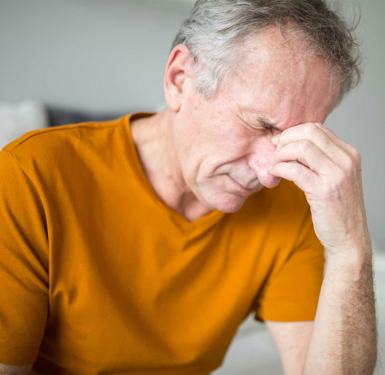 man holding the bridge of his nose in discomfort