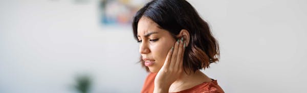 woman touching her ear in discomfort
