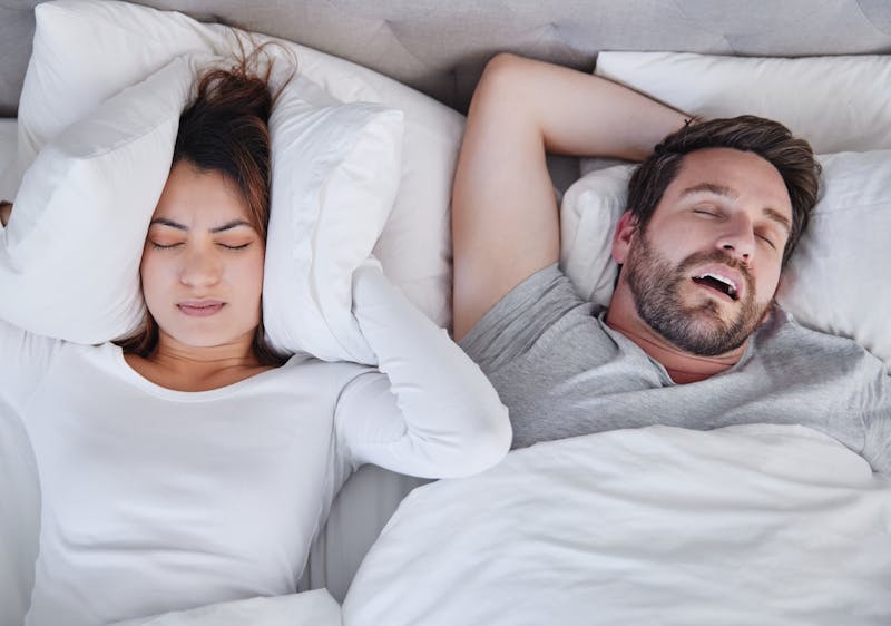 man snoring next to woman