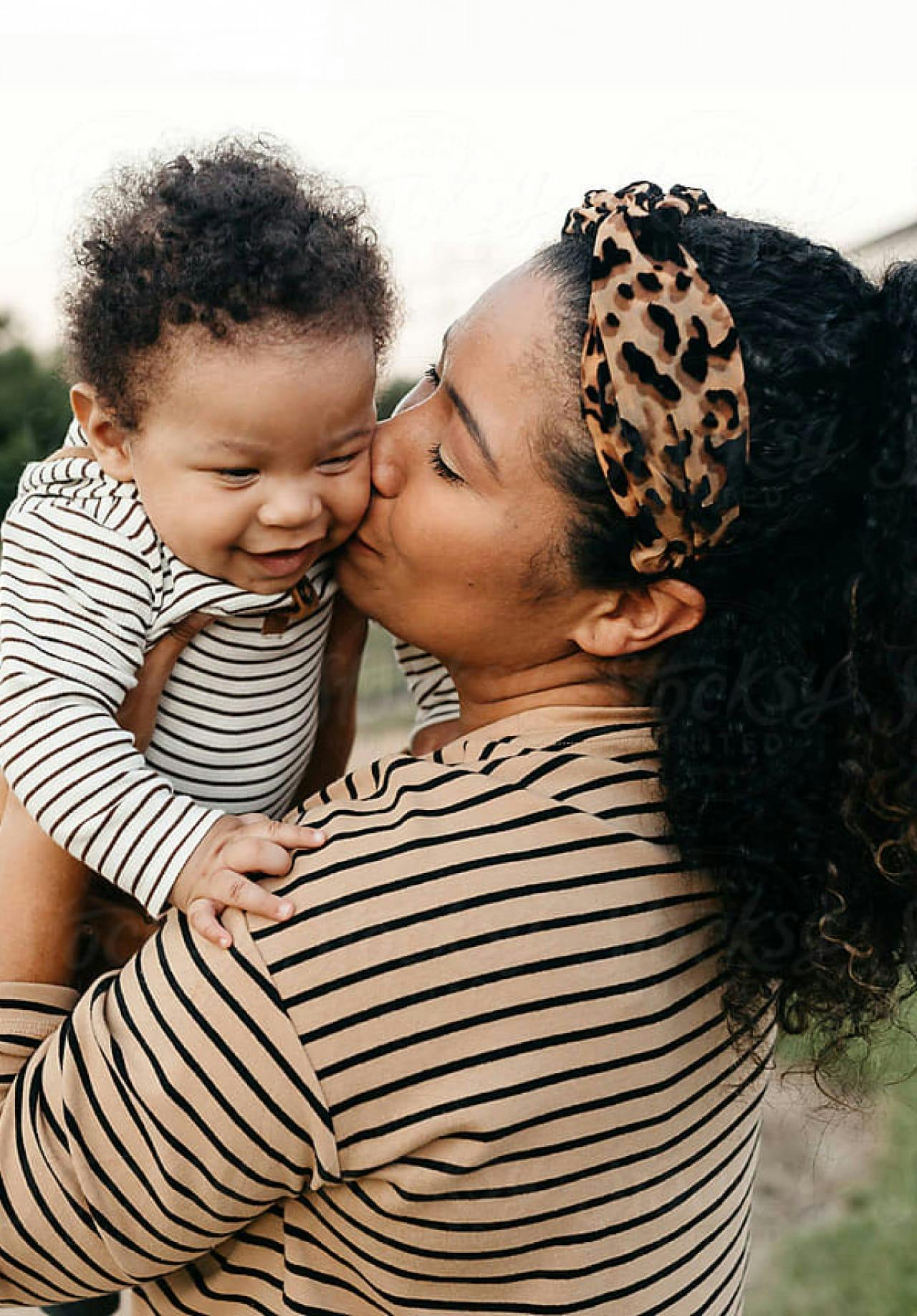 Mother kissing smiling baby on the cheek