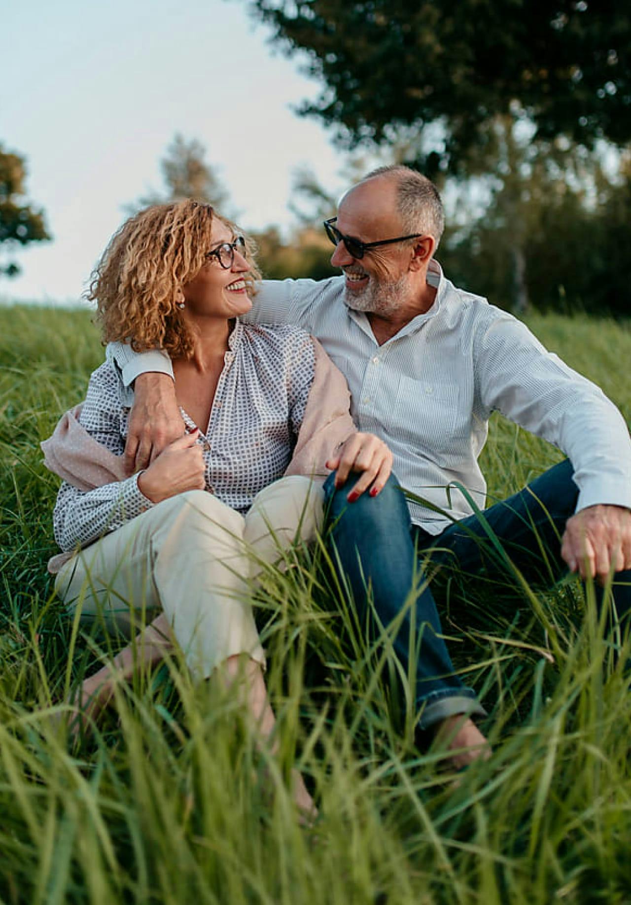 Couple sitting in the grass smiling at each other